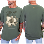 Green t-shirt with floral design and text 'Grow Through' on front, worn by a person.
