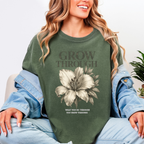 Person wearing a green sweatshirt with a floral design and text, sitting on a light-colored couch.